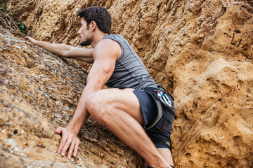 Young man climbing natural rocky wall