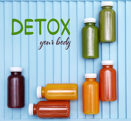 Bottles with delicious detox drinks and text detox your body on blue wooden background. Detox diet...