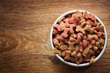 Dog food in bowl on wooden table