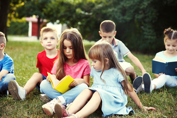 Fototapeta premium Group of happy kids reading books in park