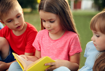 Group of happy kids reading books in park