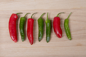 A line of red and green chilli peppers on a wooden background 