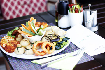 Veggi Plate for share.Tasty food. Veggi food.White plate with veggi tasty food.Restaurant table,napkin and plate with veggi food