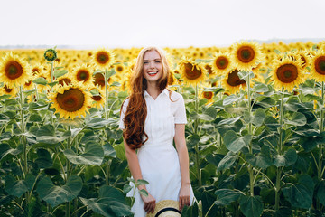 beautiful sweet sexy girl in a white dress walking on a field of sunflowers , smiling 
a beautiful smile,cheerful girl,style, lifestyle , ideal for advertising and photo sun 
shines bright and juicy