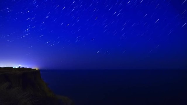 Night on the sea coast. The stars are moving with tails. Time lapse