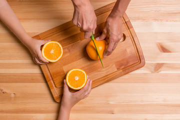 Young woman and her children with orange, top view