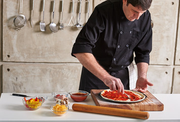 Restaurant hotel private chef preparing pizza adding toppings