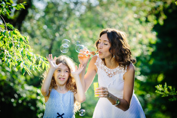 Mother and daughter blowing soap bubbles in the park