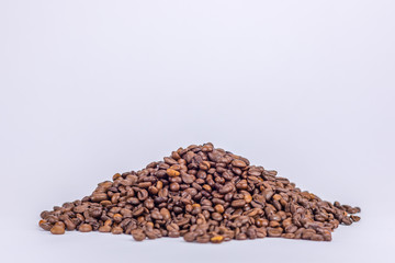 Ein Haufen aus gerösteten Kaffeebohnen auf weißem Untergrund