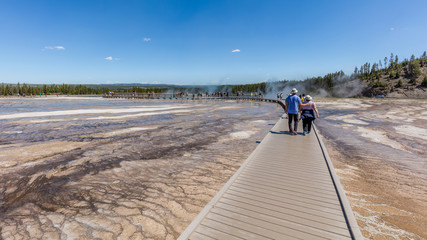 Tourists go on a tour of the wooden track. Amazing landscape of Midway Geyser Basin, Yellowstone National Park, Wyoming