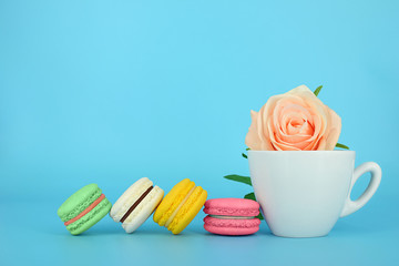 Macaroons next to a cup of rose 