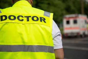 Back turned portrait of a cropped doctor wearing yellow vest
