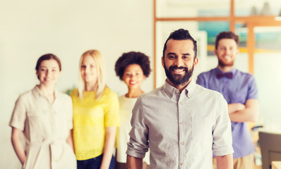 happy young man over creative team in office