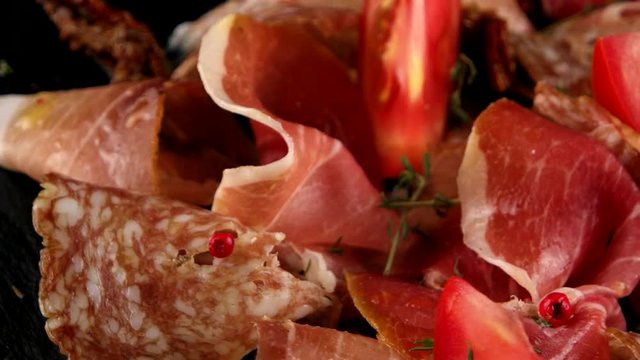 Assorted meats (ham, salami, bacon) and tomatoes, closeup