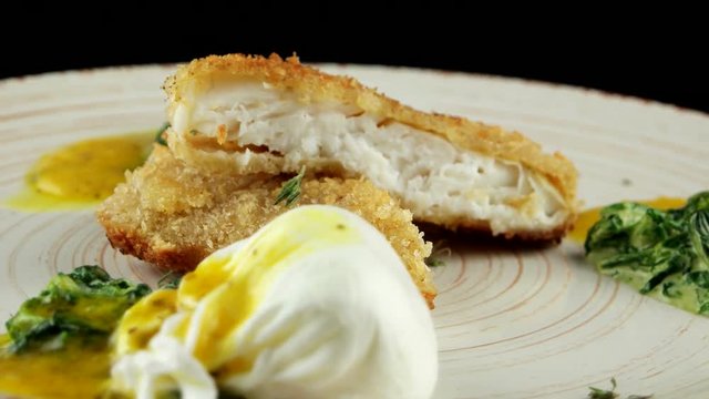 Roasted pikeperch fillet with soft poached egg and spinach, closeup, loop