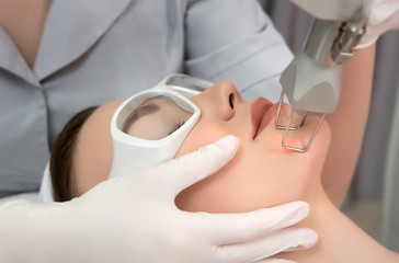 Naklejka premium Therapist beautician makes a laser rejuvenation for the model woman