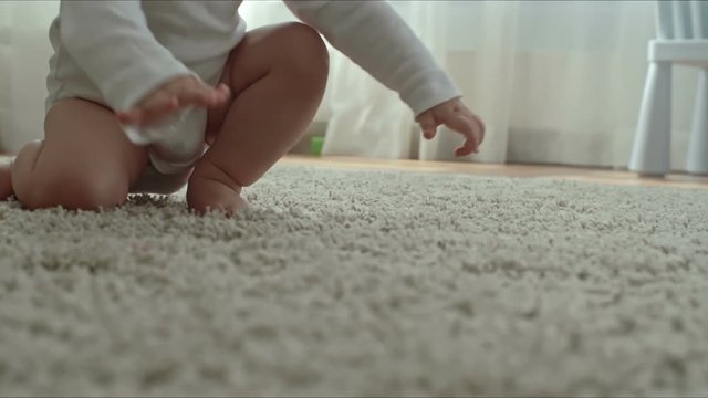 Closeup of barefoot baby crawling on soft shag rug on the floor in the living room
