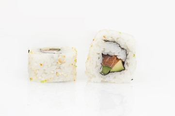 California rolls with salmon, avocado and cucumber rolled in sesame seeds, white background