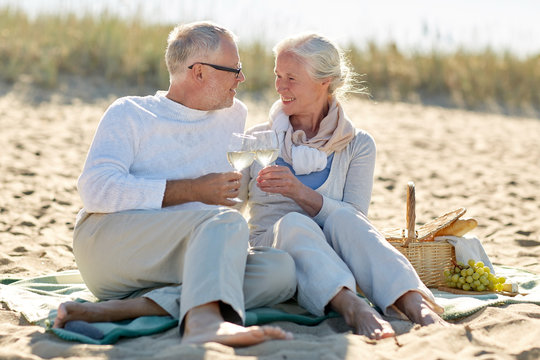 happy senior couple having picnic on summer beach