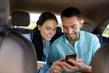 man and woman with smartphones driving in car
