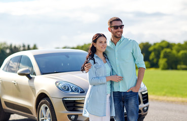 happy man and woman hugging at car