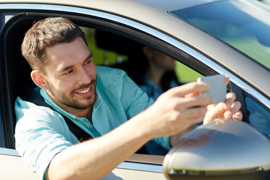 happy smiling man with smartphone driving in car