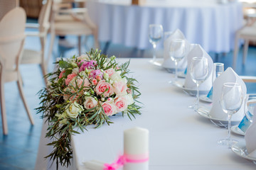 Table set for an event party or wedding reception. Large floral arrangement of roses and peonies