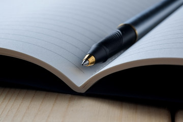 pen and book on wood background
