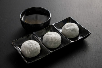 Japanese sweet black sesame daifuku on black wooden background