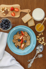 breakfast of cereal, fruit, cookies in a blue plate on a brown wooden table. view from above. a table for breakfast.