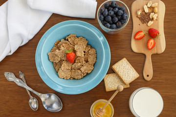 breakfast of cereal, fruit, cookies in a blue plate on a brown wooden table. view from above. a table for breakfast.
