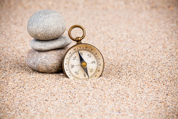 Vintage compass with pebble stones on sand