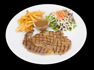 Rib eye steak served with french fries and salads to vegetables isolated on the black background with clipping path