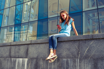 City lifestyle stylish youth using a smartphone sitting against