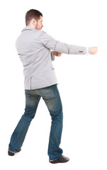 back view of standing man pulling a rope from the top or cling to something.  Rear view people collection.  backside view of person.  Isolated over white background. A guy in a gray jacket waving his