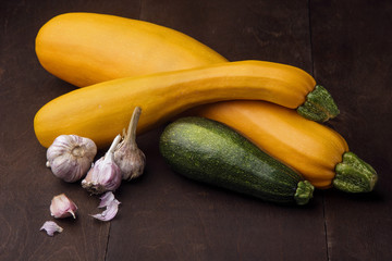 Two yellow big and medium and small green zucchini on wooden table.Family of zuccini.