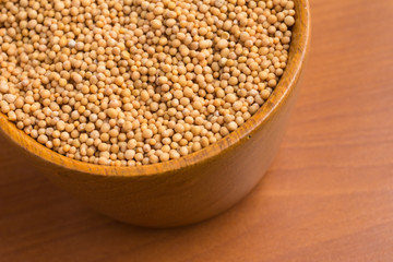Mustard seeds into a bowl over a wooden table