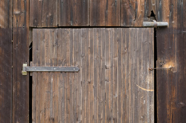 detail of a an old weathered wooden barn door with metal hinge