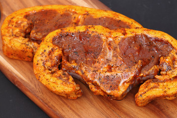 Raw lamb chops with a mint sauce marinade on a wooden chopping board