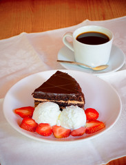 Chocolate cake with ice cream and cup of coffee. Selective focus on cake