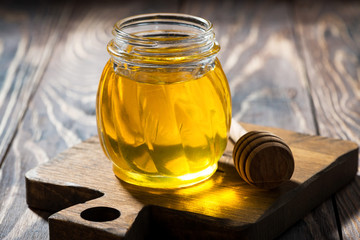 jar of fresh honey on a dark wooden table, closeup