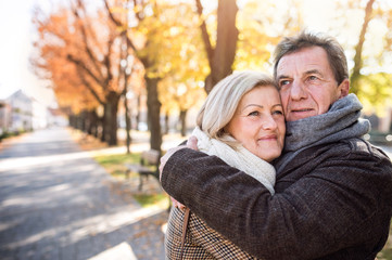 Beautiful senior couple hugging in park. Sunny autumn nature.
