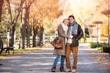Beautiful senior couple hugging in park. Sunny autumn nature.