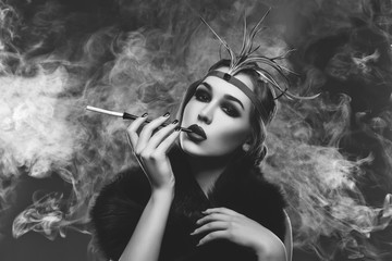Beautiful girl with smoky eyes and red lips holding cigarette