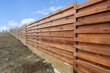 Fototapeta na wymiar Long wooden cedar fence against blue sky
