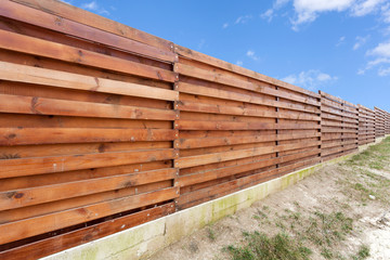 Long wooden cedar fence against blue sky