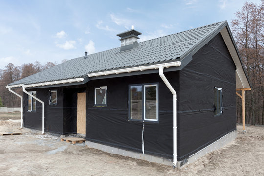 SIP panel house with new gray metal tile roof,white rain gutter and insulation