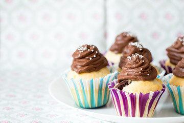 Vanilla-chocolate cupcake with topping on a light floral background.