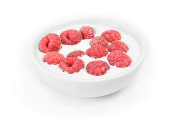 Ripe raspberry into milk in the bowl on white