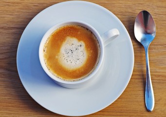 Cup of coffee on a rustic wooden served table ready for breakfast.